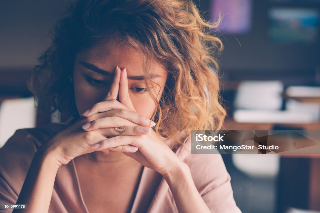 Tired Young Woman Leaning Head on Hands Closeup of sad young Asian woman at cafe leaning head on clasped hands and staring into vacancy. Tired freelancer feeling burnout. Stress and bad news concept Women Stock Photo
