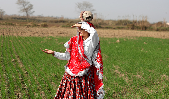 Female farmer standing portrait near wheat crop field during springtime.