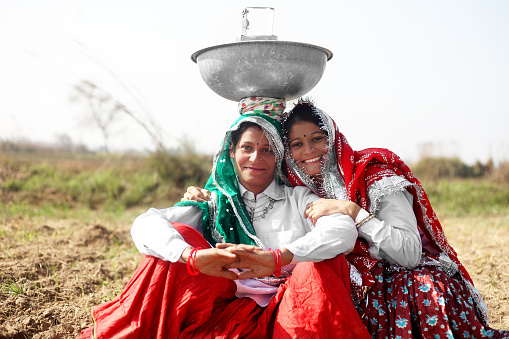 Two women of Indian ethnicity portrait together outdoor in nature. The both are wearing traditional Indian clothes.
