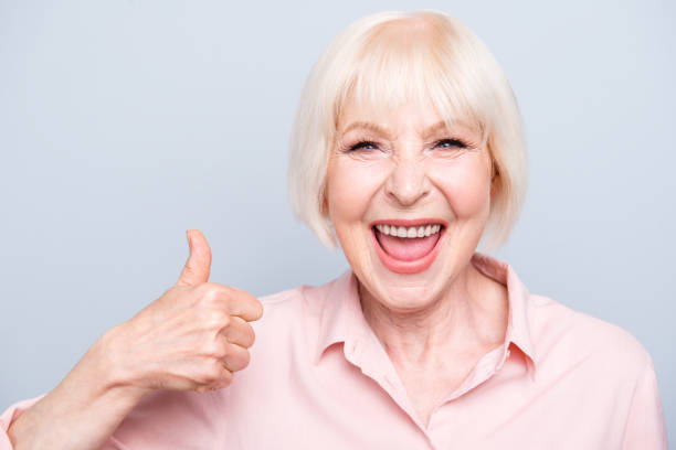 istock Old excited lady showing thumbs up gesture, laughing on grey background 1041009352
