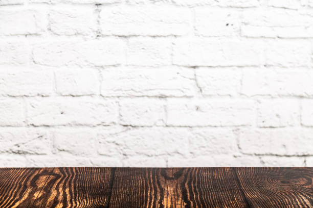 istock White brick wall texture and wooden desk on a foreground 1041013420