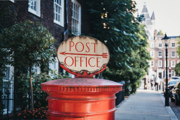 Red post box with a Post Office directional  sign in London, UK.