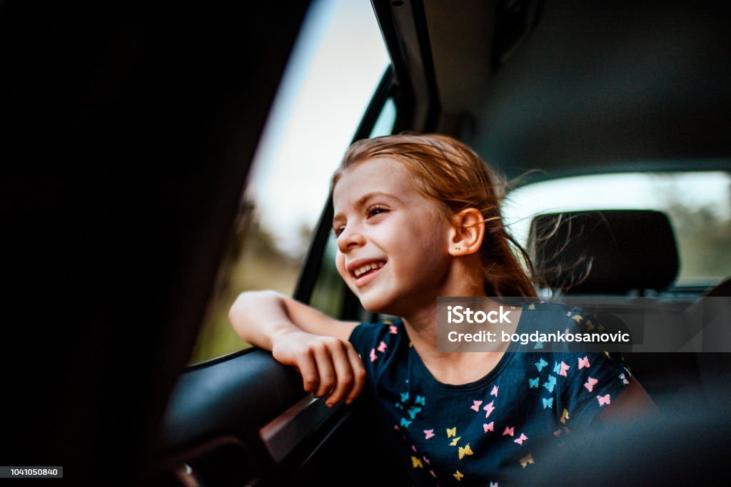 Girl looking out car window Young cute girl out car window from backseat during the road trip Car Stock Photo
