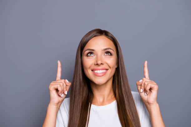 istock Young charming brunette in gesturing up with fingers isolated on gray background 1041080424