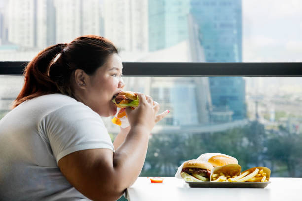 istock Fat woman eating a hamburger in the restaurant 1041088768