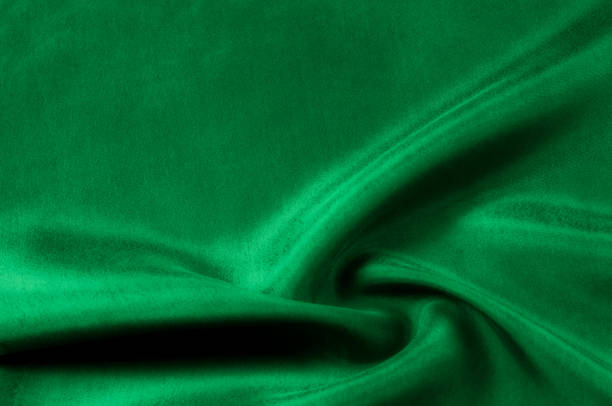 istock Background texture, pattern. Thick thick silk fabric is green. This satin fabric is ideal for creating a smooth flow in design, it has a liquid drape and exquisite shine. 1041093818