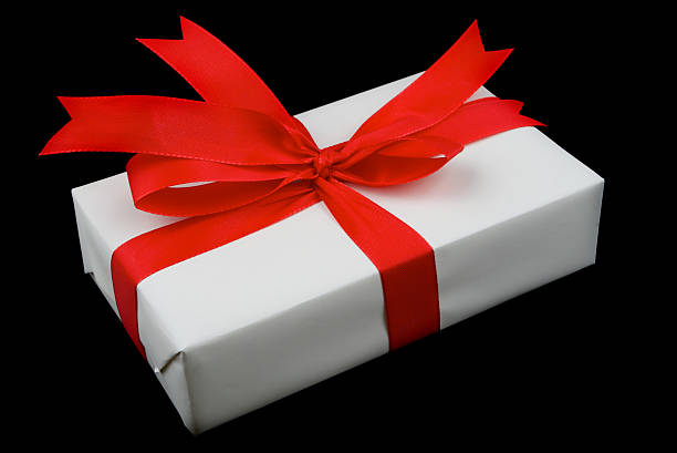 white present with red ribbon isolated on black background stock photo