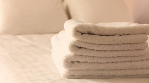 istock Hotel bedroom. White fluffy, folded towels, linen sheets and pillows on bed. Close up view. 1041097952
