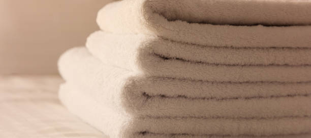 istock Hotel bedroom. White fluffy, folded towels, linen sheets and pillows on bed. Close up view. 1041097958