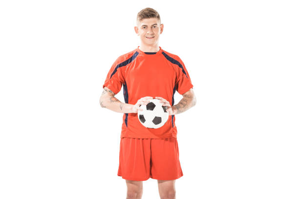 istock handsome young soccer player holding ball and smiling at camera isolated on white 1041103564