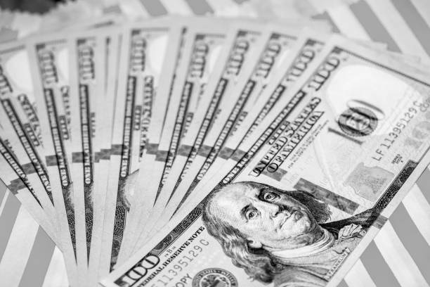 istock Hundred Dollar Bills fanned on Red & White Background (B&W Green Filtered) 1041111360