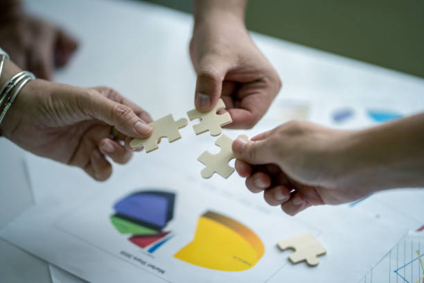istock Human hand are connecting jigsaw puzzle.Business and partnership teamwork concept in selective focus 1041113794