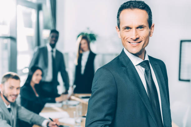 istock handsome businessman looking at camera in conference hall with multiracial partners blurred on background 1041114466