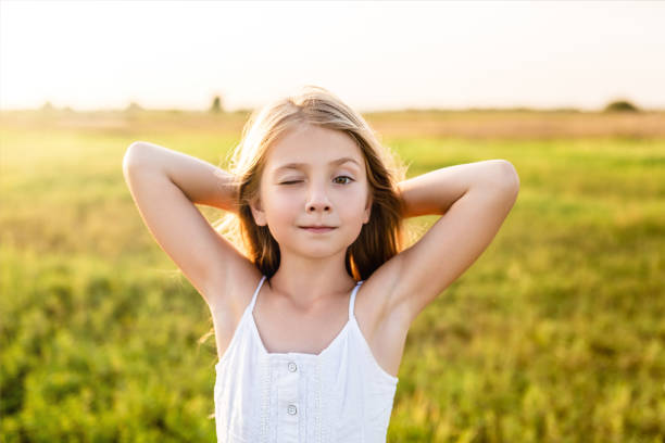 istock adorable little child winking at camera on green field under sunset rays 1041116154