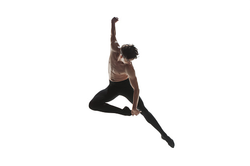 Athletic ballet dancer in a perfect shape performing over the white background.