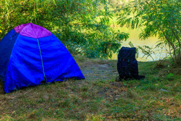 istock Blue camping tent and backpack in forest near a river 1041118436