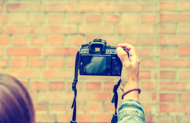 istock Woman holding a camera in hand on a brick wall background 1041125384