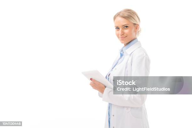 Happy Young Female Doctor Working With Tablet And Looking At Camera Isolated On White Stock Photo - Download Image Now