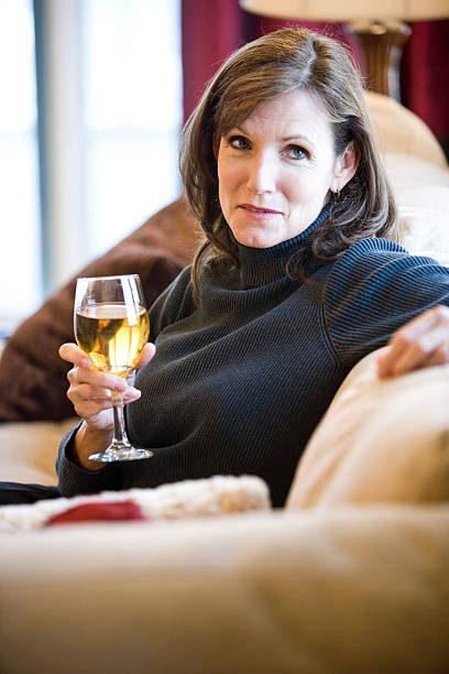 istock Mature woman relaxing on sofa drinking wine 104113139