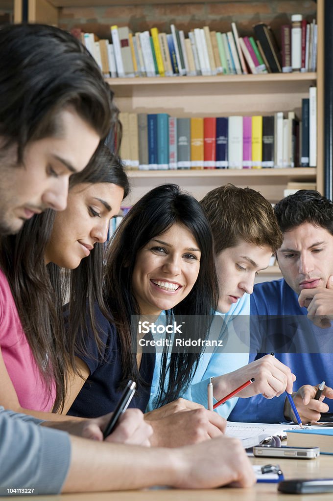 Happy students in college library Group of young teenager students working and studying in a college library, smiling girl looking at camera. Book Stock Photo