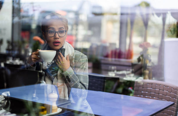 istock Young blondie asian female drinking coffee and looking through window. 1041144388