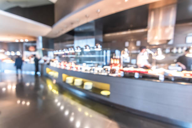 Buffet at hotel restaurant interior blur background with blurry open kitchen counter bar of food catering service business with chef staff cooking for breakfast, lunch or dinner meal