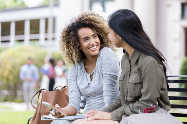 istock Young woman shares mobile app with college classmate 1041145520