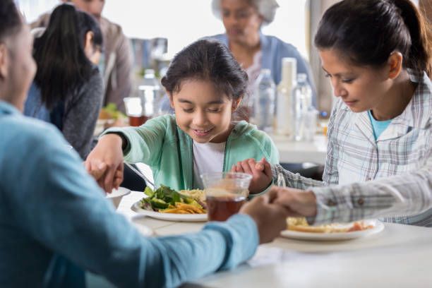 istock Family prays together before soup kitchen meal 1041147338