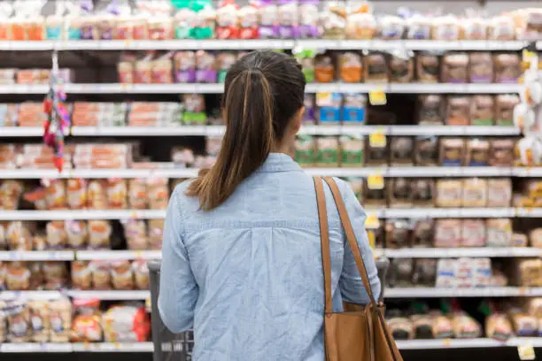 Photo of Unrecognizable woman marvels at grocery bread selection