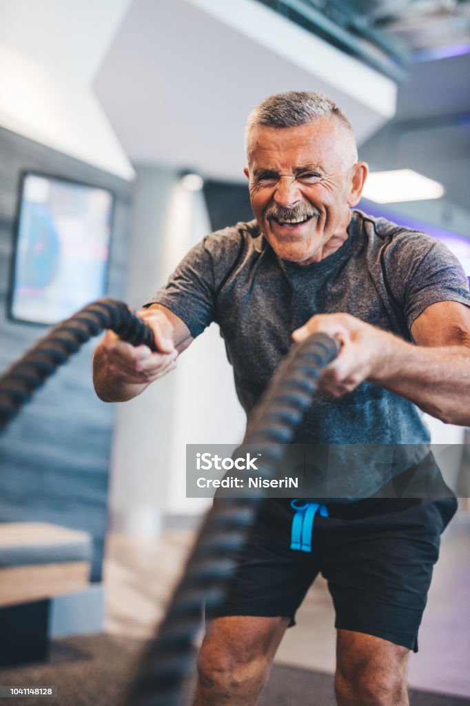 Senior man exercising with ropes at the gym. Senior man exercising with ropes at the gym. Physical activity and healthy lifestyle. Senior Adult Stock Photo