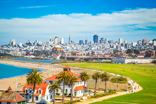 Panoramic view of San Francisco skyline with historic Crissy Field and former USCG Fort Point Life Boat Station (LBS) in the foreground on a beautiful sunny day with blue sky and clouds in summer, California, USA