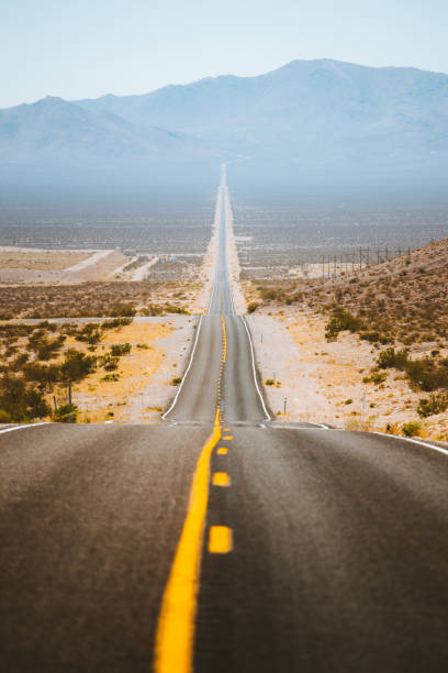 Classic panorama view of an endless straight road running through the barren scenery of the American Southwest with extreme heat haze on a beautiful sunny day with blue sky in summer