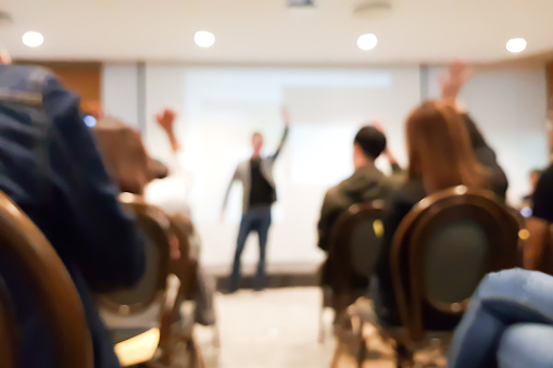 Siga borrosa grupo de personas reunidos en evento de seminario de motivación en el salón de convenciones, altavoz levantando la mano y acción de la audiencia, concepto alegre photo