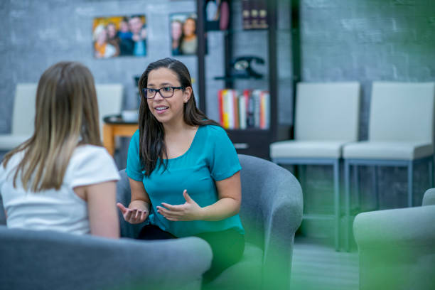 Therapist at work A woman in her early 30s explains something to a client who is sitting across from her. She looks passionate about what she is saying. career counseling stock pictures, royalty-free photos & images