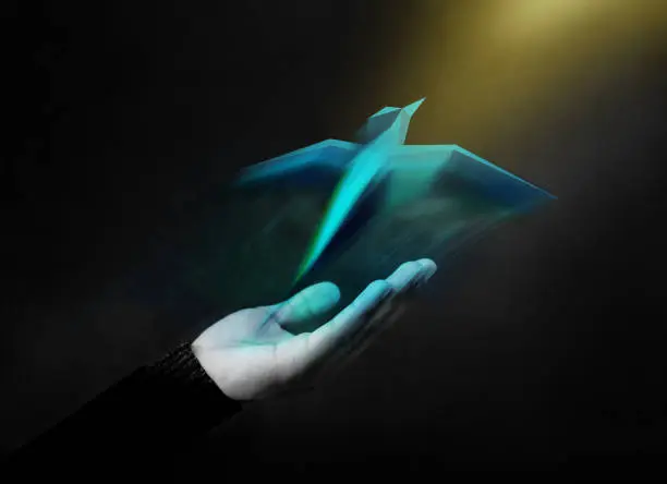 Photo of Freedom Concept. Digital Geometric Bird Soaring Up from an Opened Hand into the Golden Light