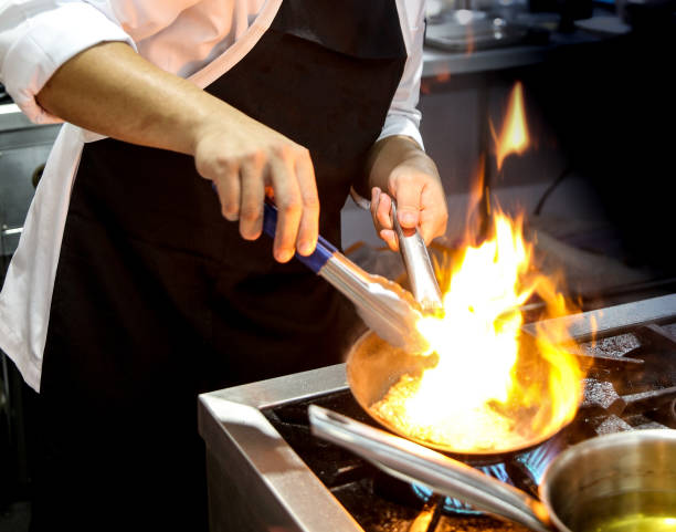 istock Chef cooking with flame in a frying pan on a kitchen stove 1041175156