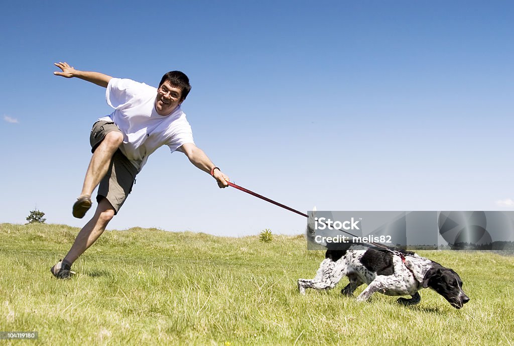 Man being dragged by his black and white dog outside Man playing with his dog Dog Stock Photo