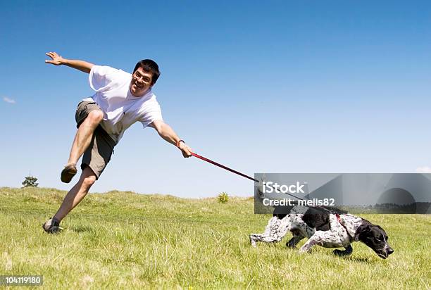 Man Being Dragged By His Black And White Dog Outside Stock Photo - Download Image Now