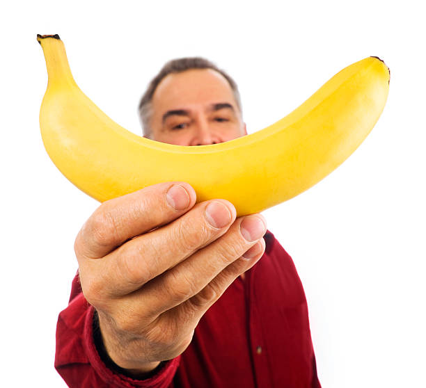 uomo tiene banana davanti al suo viso - men banana holding cut out foto e immagini stock