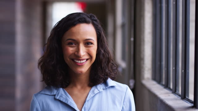 Young mixed race businesswoman turning to camera, laughing