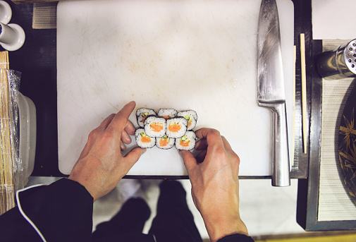Sushi Chef preparing Sushi in his kitchen, hands , top view