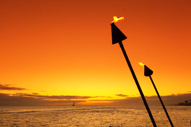 Fire lit tiki torches along the beach of Kauai Hawaii at sunset