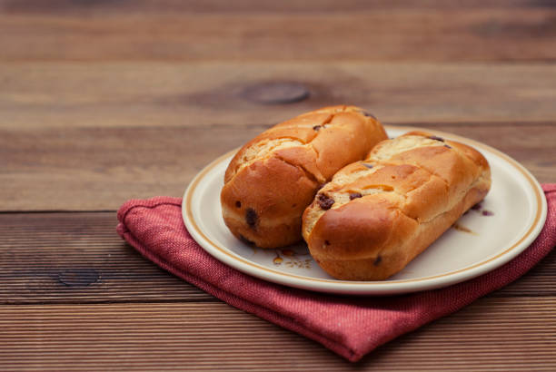 Traditional Buns in round plate and napkin,with chocolate chips, breakfast or snack, rustic wood table.