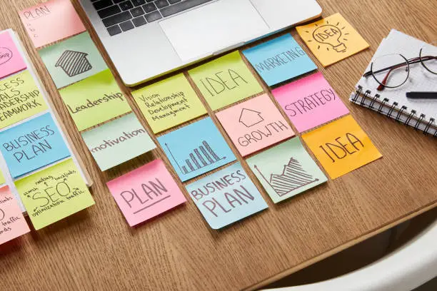 high angle view of paper stickers with business strategy and laptop on tabletop