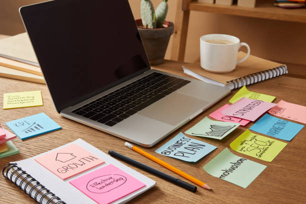 istock laptop with blank screen and paper stickers with business plan on tabletop 1041260418