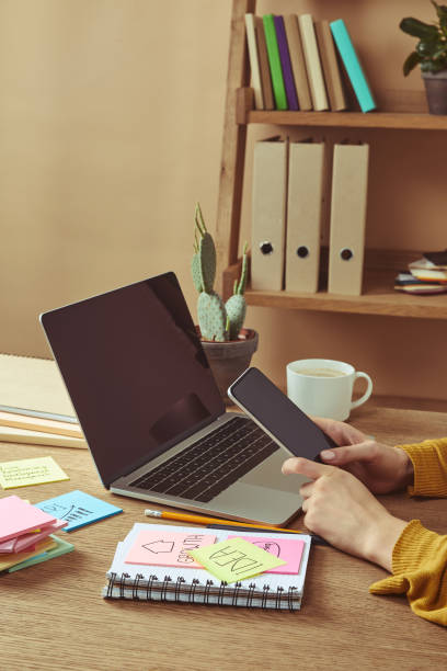 istock cropped image of woman holding smartphone with blank screen at table with note paper sheets 1041260502