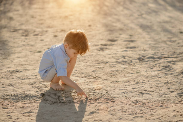 istock Three year old toddler boy playing on beach 1041271404
