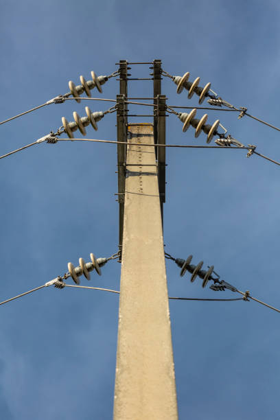 Detailed view of an electricity post, with electric cables, blue sky as background