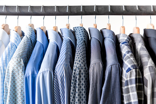 Row of men's shirts in blue colors on hanger