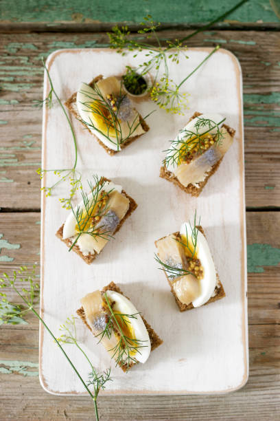 Tradition Danish open sandwich smorrebrod with herring, egg, mustard and dill. Dark bread sandwich.